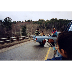 Woman looks out her automobile window to see a pickup truck marked "taxi" transporting four adults and two children from the International Paper Company march and strike