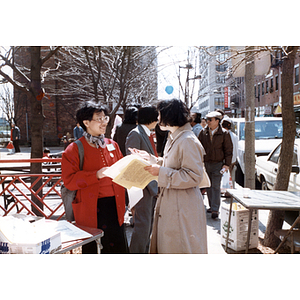 Suzanne Lee talks with a woman about the Chinese Progressive Association and elections in Boston