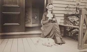 Betsy Wilder seated on piazza, with dog at her feet