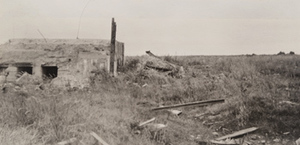 View of a damaged concrete fortification in a grassy field