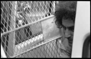 Abbie Hoffman in a police van, getting arrested for wearing an American flag shirt