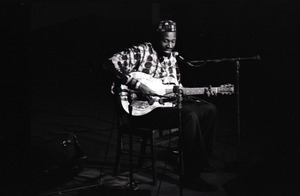 Taj Mahal in concert at Northfield, Mass.: Taj Mahal seated, playing steel guitar