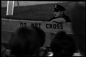 Beatles concert at Shea Stadium: Policeman providing concert security, leaning on a barrier reading 'Do not cross'