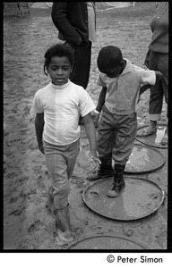 Children walking through the mud, using oil drum lids as stepping stones, Resurrection City encampment