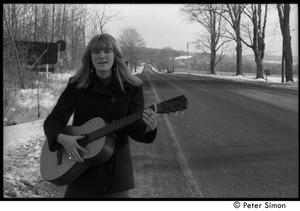 Karen Helberg standing in the road, playing acoustic guitar