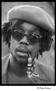 Peter Tosh: portrait wearing beret, dark glasses, and smoking a pipe