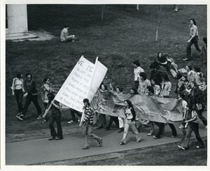 Board of Trustees fee increase demonstration: protestors holding banner and sign, marching from the Student Union to the Whitmore Administration Building