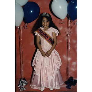 A girl poses in a dress and crown at the Festival Puertorriqueño