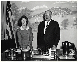 Unidentified woman signing a bound volume with unidentified man in Mayor Collins's office