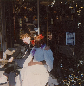 A Photograph of Marsha P. Johnson Sitting with a Friend Wearing a White Dress and Floral Headpiece