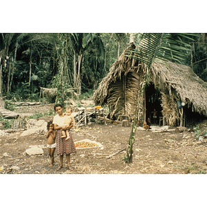 Woman standing with baby and child outside their home