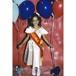 A girl dons a Caguas sash and holds balloons at the Festival Puertorriqueño