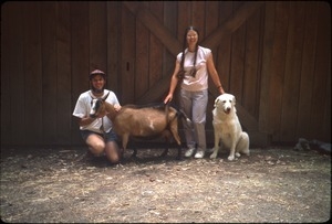 Mark and Sandi Sommer in front of barn with Maya the dog and Kate (mama goat)
