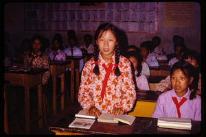 Shijiazhuang Production Brigade: young schoolgirl in classroom, standing and reading aloud