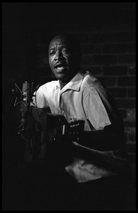 Josh White performing on guitar in a coffeehouse