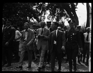 Harvey Firestone, Henry Ford, and Barclay Fernald walking (l. to r.), flanked by police officers