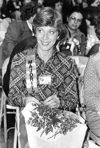 Delegate wearing majority ribbon and working on needlepoint at the First National Women's Conference