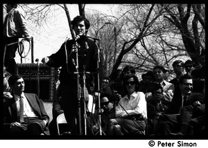 Resistance on the Boston Common: Terry Cannon (draft resister and member of the Oakland 7) addressing the crowd, Howard Zinn (far left) and Noam Chomsky (far right) seated on stage