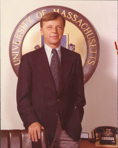 David C. Knapp standing behind desk in front of University of Massachusetts logo
