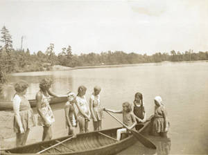 Girls standing around canoe at Camp Massasoit