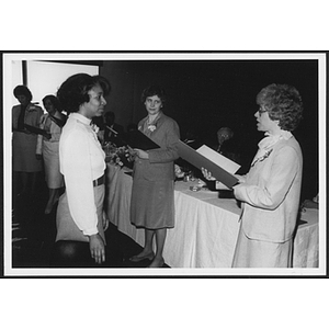 Woman stand next to a long table, holding folders