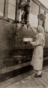 Red Cross worker offering cigarettes to a soldier through a train window