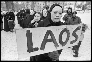 Protesters from Bread and Puppet Theater, dressed in cloaks and masks and carrying a sign reading 'Laos,' during a demonstration against the invasion of Laos at the Vermont State House