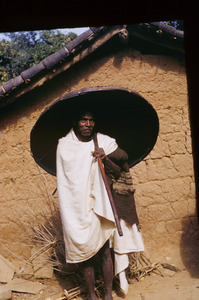 Munda man carrying an umbrella woven from cane or bamboo