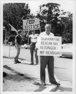 Man holding a sign reading 'Quarantine Reagan and Kissinger - Not Nicaragua'