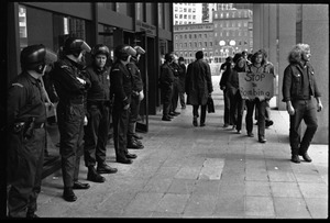 Small group of protesters file past police at the entrance to the John F. Kennedy Federal Building