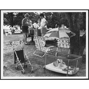 Women looking at stroller and infant in a crib nearby