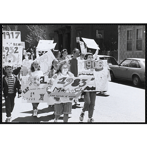 Children walking down the street with their signs during the Boys and Girls Clubs of Boston 100th Anniversary Celebration Parade