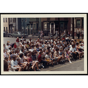 Contestants' families sit in chairs while looking to the front during a Boys' Club Little Sister Contest