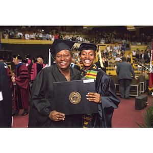 Graduates holding up diploma at commencement