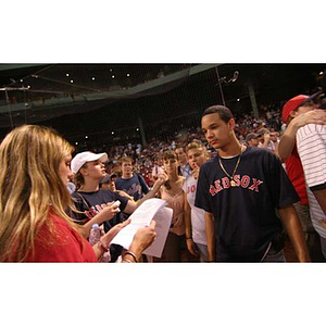 A woman holding papers stands in front of Odalis David Polanco at Fenway Park