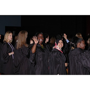 A graduate waves to audience members at the School of Nursing convocation