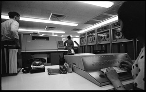 Computer room scene: woman at the console of a Honeywell Model 400 mainframe, with printer and card reader (?) in background