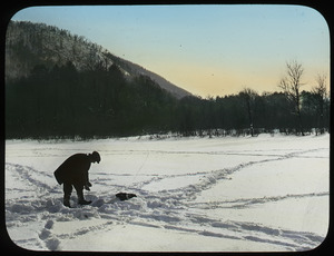 Man ice fishing on snow-covered lake