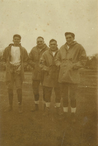 Football players pose while huddling in their coats
