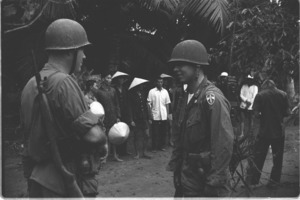 Captain Roger Horner and Lt. Walter Vlasak carrying radio on his back discussing village defense plan; Luong Hoa Village.