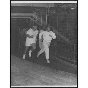 Men and boys running around indoor track