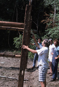 Tom Jorling hammers a wooden pin into post at north end of barn at Moon Barn Raising at entrance to Hopkins Forest on 2 August 1975.