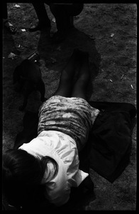 Young woman lying on a coat thrown on the ground, with puppy, Cambridge Common