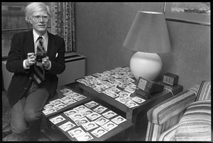 Andy Warhol seated with an array of polaroids at the Birmingham Museum of Art