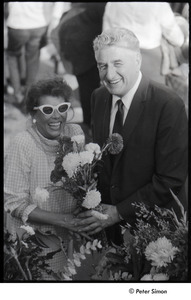 Robert Kennedy and Kenneth Keating campaigning in Riverdale: Andrea Simon holding flower bouquet with unidentified man