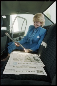 Margaret Heckler, United States Ambassador to Ireland, reading newspaper in the back of a limousine