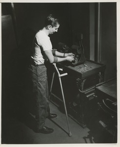 A man using forearm crutches polishes jewelry at a machine