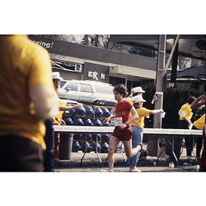 Runner in red shirt passing YMCA staff at Boston Athletic Association (BAA) marathon