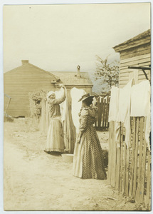Two black women hanging laundry on a fence in Tuskegee, Alabama