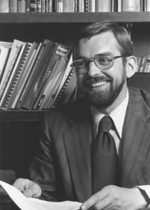 Suffolk University Dean Richard M. McDowell (SOM, 1974-1991) in front of bookshelf, 1970s